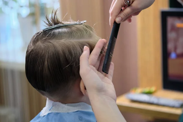 Fodrászüzlet. Fodrász teszi a frizura egy fiú, hajvágó olló és fekete fésű. — Stock Fotó
