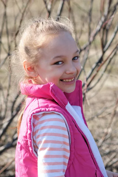 Portrait of a girl in a red vest in early spring on the background of willow — Stock Photo, Image