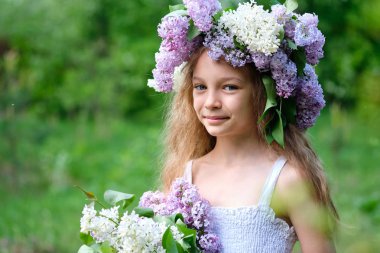 Bahar bahçesinde bir buket Lilya ve leylak çelenk ile bir kız