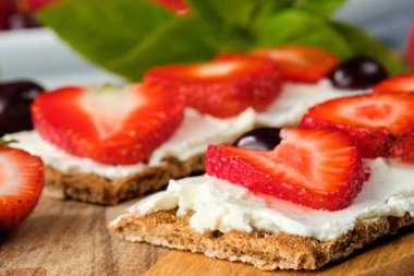 süzme peynir, taze çilek ve kiraz ahşap bir tahta üzerinde, gri bir arka planda, seçici odak ile ekmek