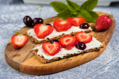 peynir, çilek ve kiraz ile somun bir kesme tahtası ve nane yaprakları ile gri arka plan