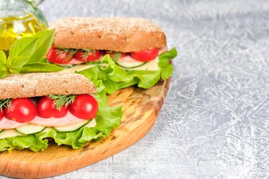 Ahşap tahta üzerinde peynir, salatalık ve kiraz domates ile sandviç. Sandviç, marul yaprağı ve kiraz domatesleriyle dekore edilmiştir..