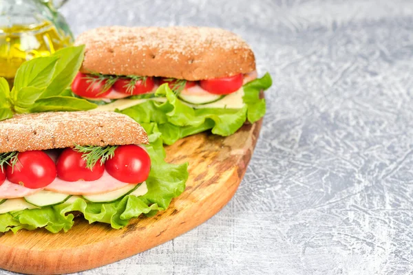 Ahşap tahta üzerinde peynir, salatalık ve kiraz domates ile sandviç. Sandviç, marul yaprağı ve kiraz domatesleriyle dekore edilmiştir..