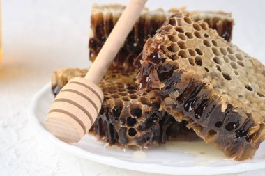 bal ile petek gri bir tabak ve bal kaşığı, seçici odak yalan