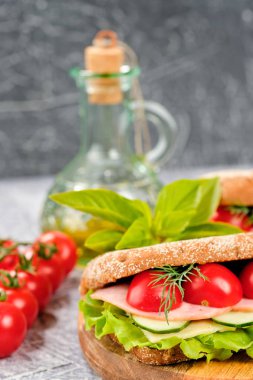 Ahşap tahta üzerinde peynir, salatalık ve kiraz domates ile sandviç. Sandviç, marul yaprağı ve kiraz domatesleriyle dekore edilmiştir..