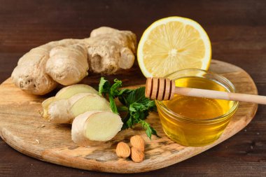 ahşap Tahta ve gri arka plan üzerinde zencefil, limon ve nane ve fındık ile bal. Yakın çekim