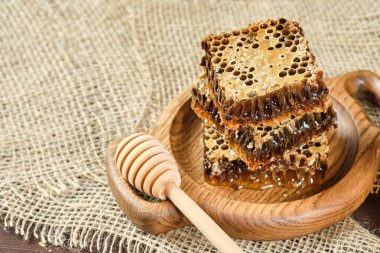 Tahta bir tabakta bal kovanında bal, ahşap bir zeminde bal kaşığı..