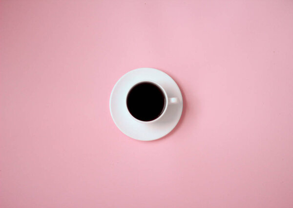 белая чашка черного кофе на розовом фоне
