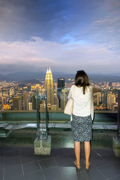 Genç bir kadın Bangkok bir gökdelen bakıyor