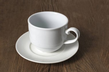 Eski ahşap bir masa üzerinde sıradan boş beyaz kahve fincanı.