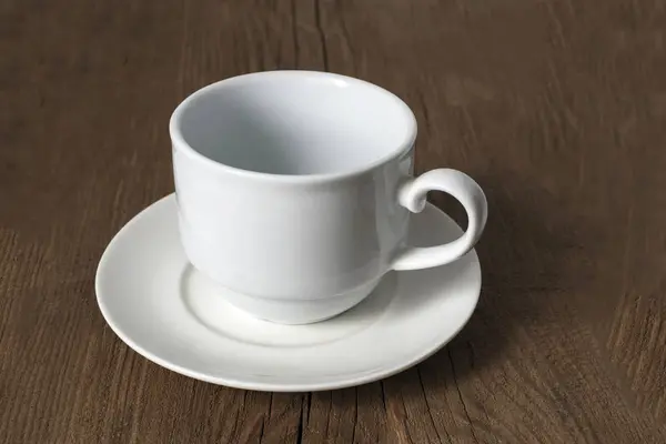 Eski ahşap bir masa üzerinde sıradan boş beyaz kahve fincanı.