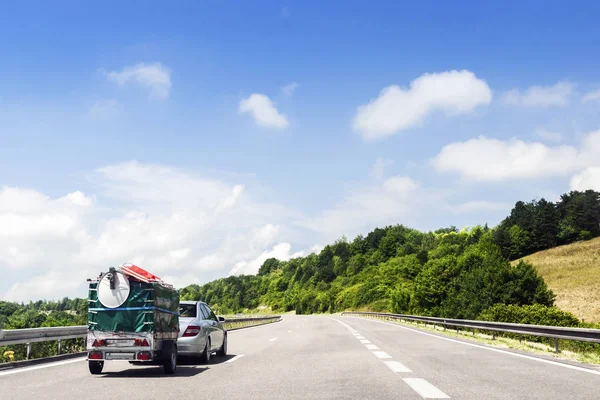 Binek otomobil yüklü bir römork ile otoyolda sürüş.