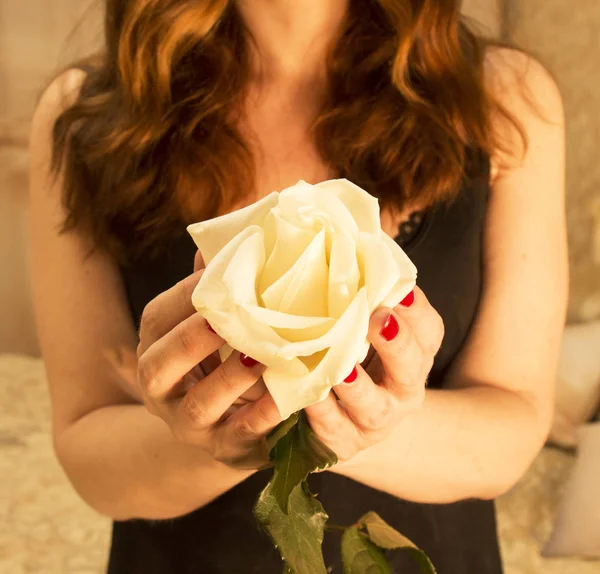 a large white rose in the hands of a red-haired girl in a black dress. Rose for sleeping beauty
