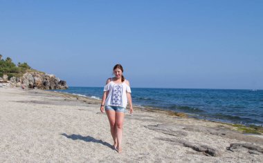 Şort ve beyaz bluz kız deniz tarafından sahilde ... Kumsalda kızıl saçlı kadın. Güneyde bir tatil