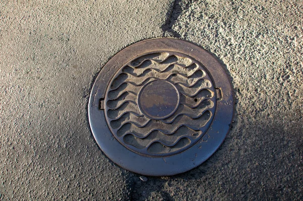 Sewer manhole on the urban asphalt road. Closeup photo Stock Photo