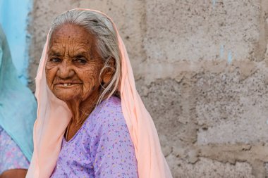 Osian, Hindistan - 22 Şubat 2015: Rajasthan'daki Osian'ın eski şehir merkezindeki evinin önünde kimliği belirsiz güzel yaşlı kadın