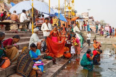 Varanasi, Hindistan - 18 Mart 2014. Varanasi 'nin eski ghatlarından kutsal Ganj Nehri' nde renkli geleneksel kıyafetleri ve Hindu dini yıkanma ritüelini gösteriyor.. 