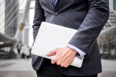 Akıllı iş adamı tutun dizüstü bilgisayar aygıt iletişim internet iş hakkında ile Toplantı ve iş bölgesinin şehir merkezinin arka plan ile fikir için 