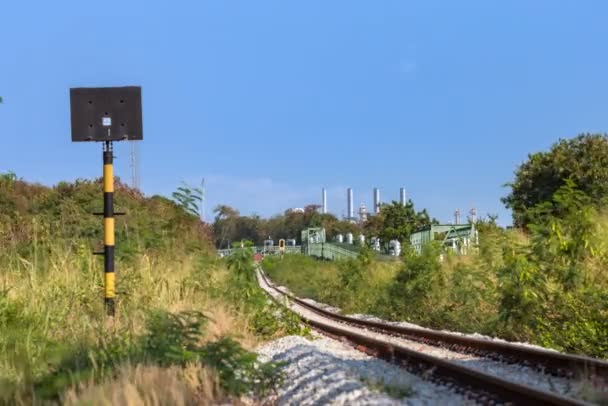 Железнодорожные рельсы с нефтехимической и нефтяной промышленностью на заднем плане и паровые трубы и изоляция с железнодорожным рельсом — стоковое видео