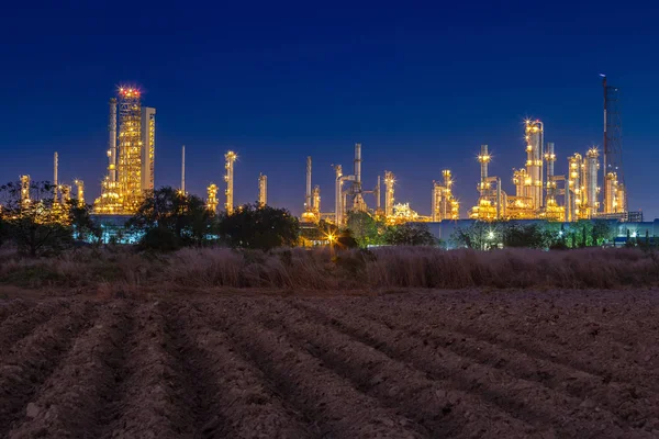 Notte dopo il tramonto con campo agricolo e impianto chimico impianto petrolchimico e petrolifero con reattore e distillazione per processo chimico industriale — Foto Stock