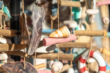 Açık hava hediyelik eşya dükkanında deniz kabuğundan ve deniz piyadelerinden yapılmış rüzgar çanları. Mesaj için yer var. Deniz hatıraları. Ahşap ve deniz kabuklarından yapılmış deniz dekorasyonu. Yatay arkaplanı kapat