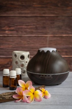 Taze frangipani çiçek, cam yağ şişeleri, bazı ham ahşap ve beyaz çay ışık mum esans difüzör