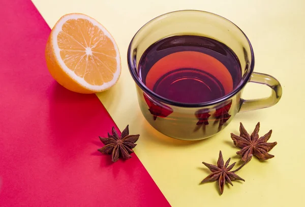 bir bardak çay, yarım limon, Anason yıldız sarı-kırmızı zemin üzerine