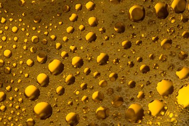 Turuncu ve sarı sıvı zemin üzerinde kabarcıklar ve damlalar.