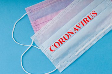 Mavi arka planda Coronavirus yazısıyla tıbbi maske 