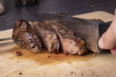 Aşçı elleri odun kesme masasında bıçakla biftek doğruyor.. 