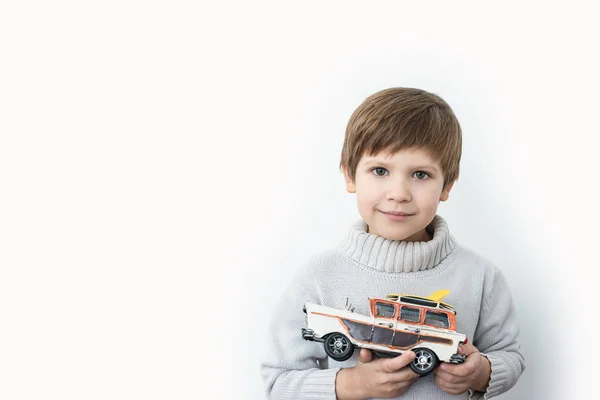 白い背景におもちゃのレトロな車を保持しているセーターの少年 — ストック写真