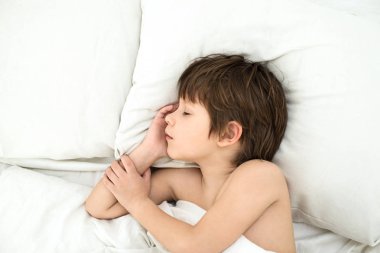 çocuk uyku, çocuk beyaz bir yatak örtüsü bir yatakta yatıyor. Üstten Görünüm. 