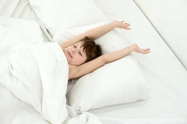 Sleeping child, boy lies in a bed on a white bedclothes. Top view. — Stock Photo, Image