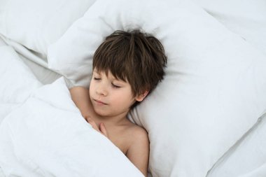 çocuk uyku, çocuk beyaz bir yatak örtüsü bir yatakta yatıyor. Üstten Görünüm. 