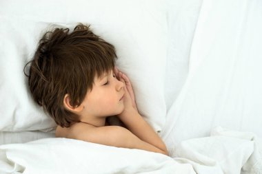 çocuk uyku, çocuk beyaz bir yatak örtüsü bir yatakta yatıyor. Üstten Görünüm. 