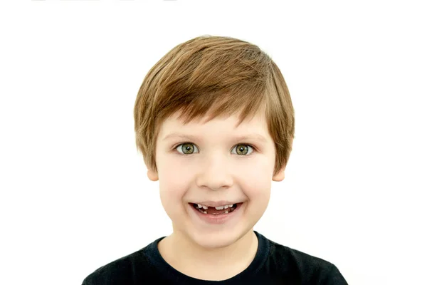 Смеющийся мальчик без молочного зуба, отсутствие молочного зуба, выпавший из ребенка зуб, беззубая улыбка, стоматолог, белые зубы ребенка, черная футболка на белом фоне, отсутствие молочного зуба — стоковое фото