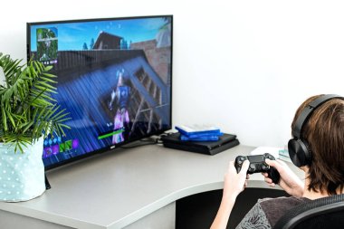 Genç bir fortnite bilgisayar oyun kulaklıklar ve bir joystick, oyun konsolu, Sony Playstation 4 çalış,