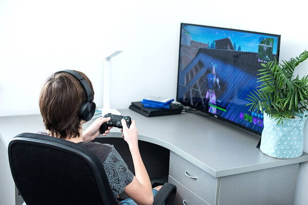  A teenager plays a fortnite computer game with headphones and a joystick, game console, Sony Playstation 4