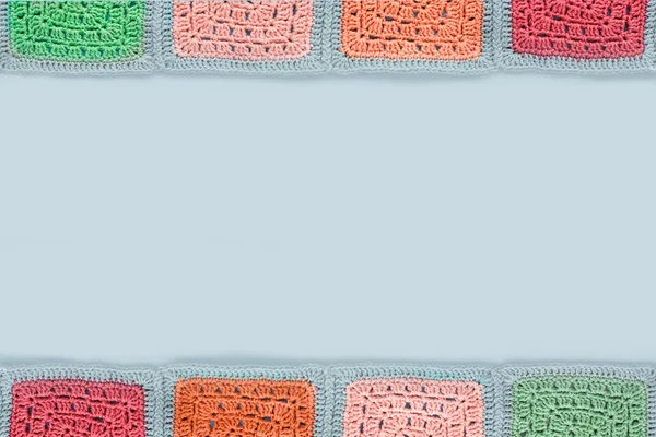 Crocheted  lace tablecloth of multicolored squares ornament on a gray background, top view, place for text, natural wool — Stock Photo, Image