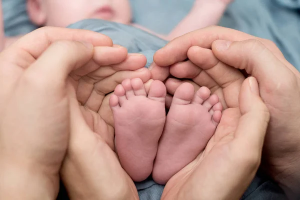 Voeten van een pasgeboren baby, tenen in de handen van mama en papa, handen en nagels van een kind, de eerste dagen van het leven na de geboorte, schilferige huid — Stockfoto