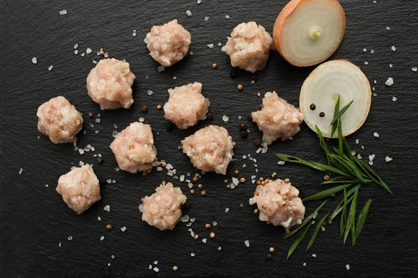 Ingredientes para fazer sopa com almôndegas. carne crua, cebolas e macarrão em uma placa de pedra preta . — Fotografia de Stock