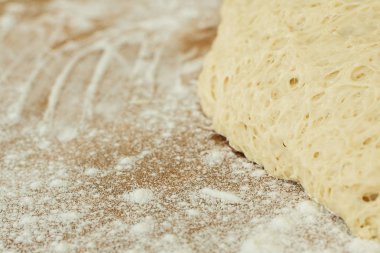 ahşap kesme tahtası üzerinde yalan hamur un serpilir