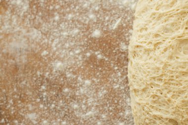 ahşap kesme tahtası üzerinde yalan hamur un serpilir