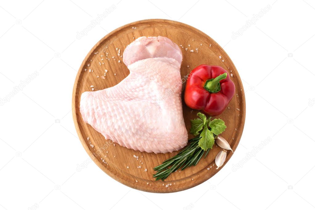 raw turkey wing, part of chicken poultry carcass, on a wooden round board with pepper and rosemary on a white background, isolate