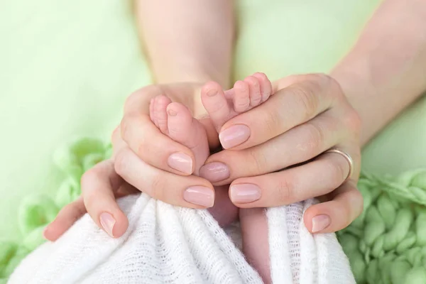 Mãe segura os pés do bebê recém-nascido com as mãos, dedos no pé, cuidados maternos, amor e abraços familiares, ternura . — Fotografia de Stock