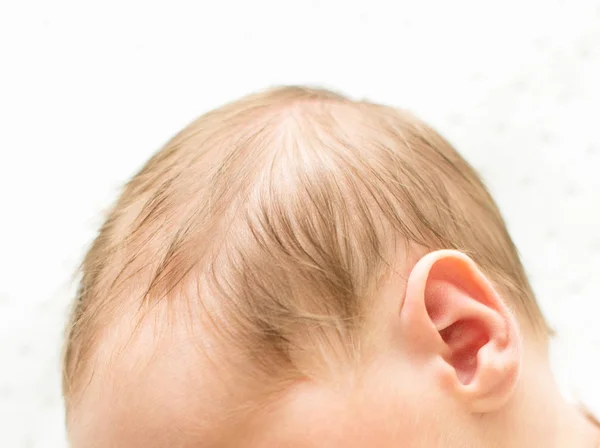 Cabeza del bebé recién nacido escuchar por primera vez en el fondo blanco, oído del bebé de cerca, macrodisparo del audífono, dolor de oído , — Foto de Stock
