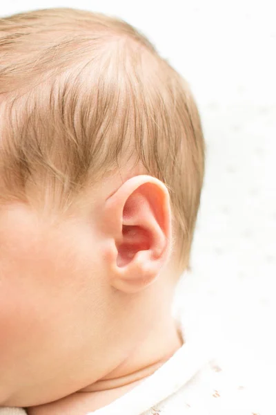 Kopf des Neugeborenen zuerst auf weißem Hintergrund hören, Babyohr aus nächster Nähe, Makroaufnahme des Hörgeräts, Ohrenschmerzen, — Stockfoto