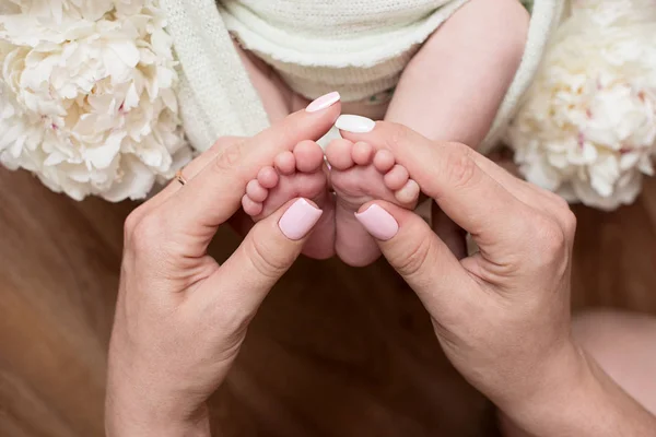 Mutter hält die Füße des Neugeborenen mit Händen, Fingern am Fuß, mütterliche Fürsorge, Liebe und Umarmungen in der Familie, Zärtlichkeit. — Stockfoto