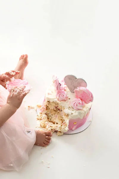 Crash Pink cake bij de viering van de eerste verjaardag van het meisje, geruïneerd spons cake, gebroken Marshmallow, baby handen en vertragingen. permissiviteit, ongehoorzaamheid, eten met handen — Stockfoto