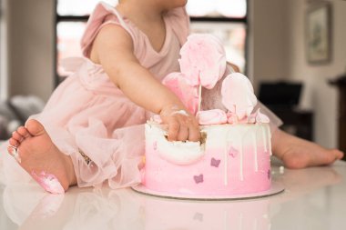 Kız ilk Doğum günü kutlamasında Crash pembe kek, harap sünger kek, kırık Marshmallow, bebek elleri ve gecikmeler. permissiveness, itaatsizlik, eller ile yeme